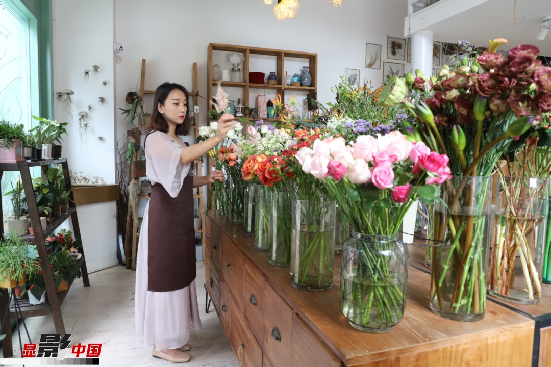 王黎媛是一名河南姑娘，在昆明念完大學后，就再也舍不下春城的藍天陽光、青山碧水，更舍不下這里的四時繁花，于是就干脆留了下來，成了一名媒體人。2017年的時候又毅然辭去工作，創(chuàng)業(yè)開起了花店，成了都市里的一名“花房姑娘”。圖為王黎媛在自己的花店中整理鮮花。新華網 周亞平/攝 念新洪/文